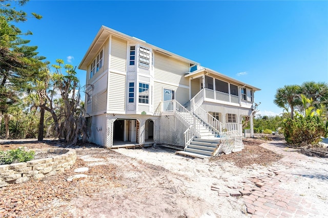 view of front of home with stairway and a sunroom