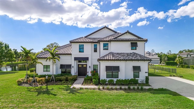 view of front of property featuring a tile roof, fence, driveway, and a front lawn