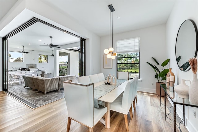 dining space with a healthy amount of sunlight, an inviting chandelier, light wood-style flooring, and baseboards