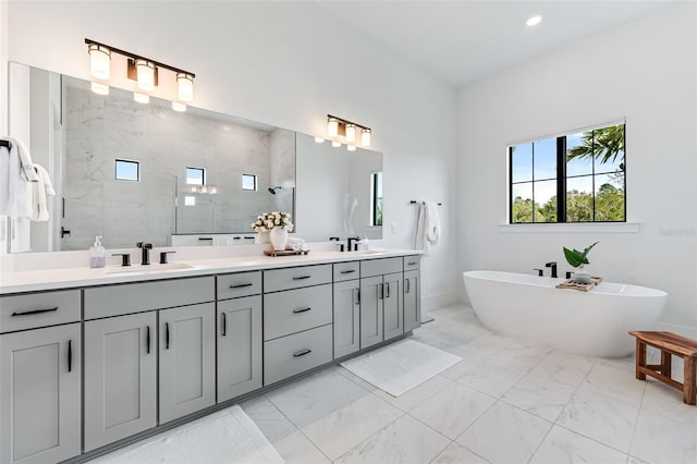 bathroom featuring double vanity, a soaking tub, marble finish floor, a walk in shower, and a sink