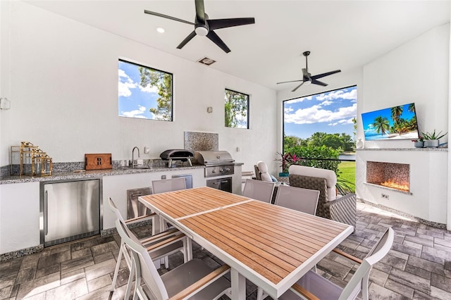 dining space featuring visible vents, a ceiling fan, stone finish flooring, a lit fireplace, and recessed lighting