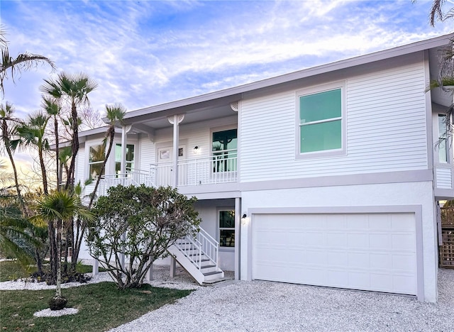 view of front of property with an attached garage, gravel driveway, and stucco siding