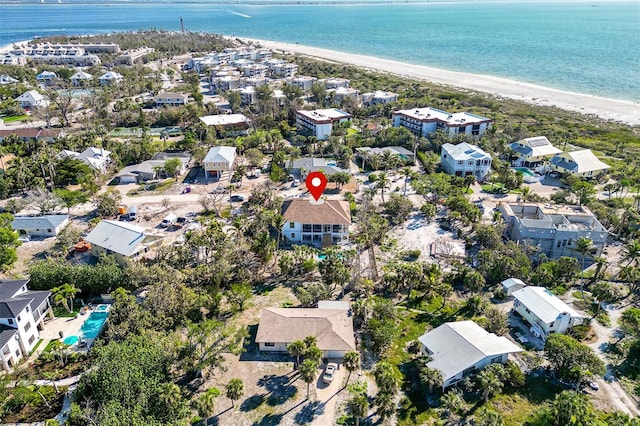 drone / aerial view featuring a water view, a residential view, and a beach view