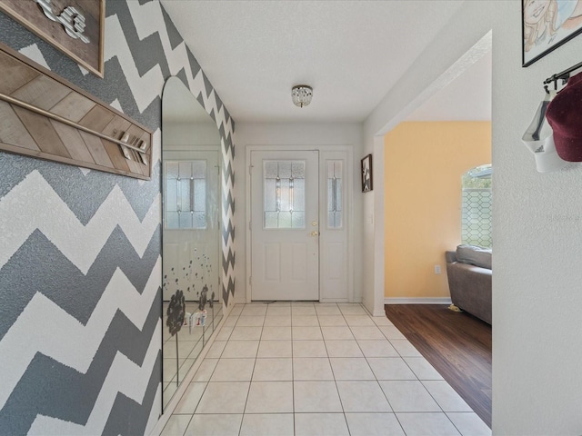 entrance foyer with light tile patterned floors, a textured ceiling, a wealth of natural light, and baseboards