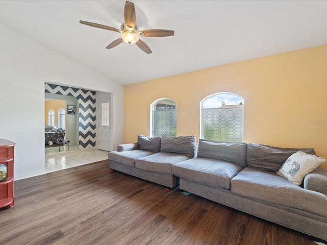 living room with a ceiling fan, vaulted ceiling, and wood finished floors