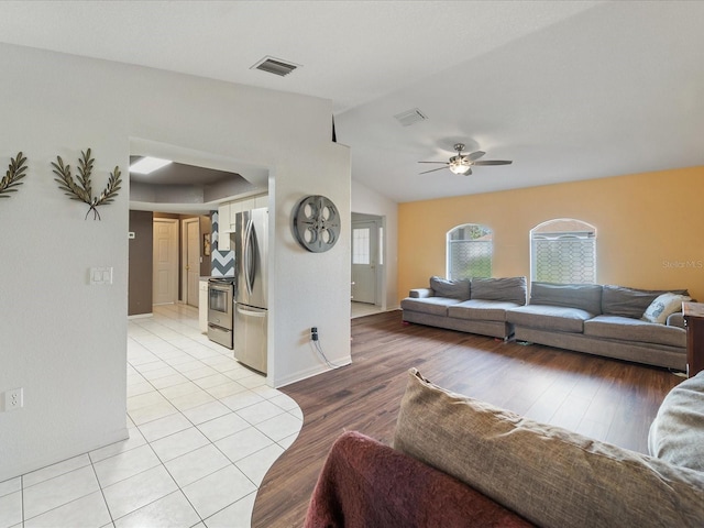 living area with vaulted ceiling, ceiling fan, light wood finished floors, and visible vents