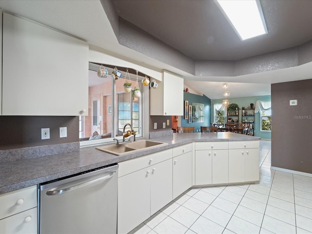 kitchen featuring dishwasher, a peninsula, a sink, and white cabinetry