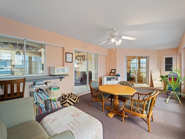 carpeted dining space with ceiling fan