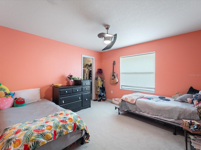 bedroom featuring ceiling fan, a walk in closet, a textured ceiling, carpet floors, and a closet