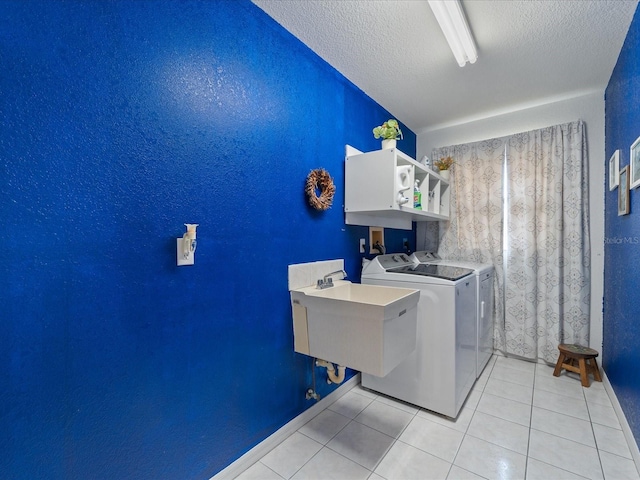 laundry area with a textured ceiling, light tile patterned flooring, laundry area, a sink, and independent washer and dryer