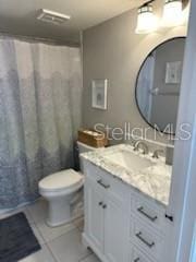 bathroom with a shower with shower curtain, vanity, toilet, and tile patterned floors