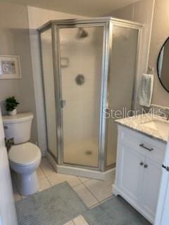 full bathroom featuring a stall shower, vanity, toilet, and tile patterned floors