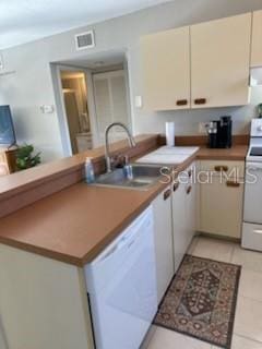 kitchen featuring white appliances, visible vents, a sink, and light tile patterned floors