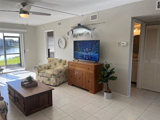 living area with a ceiling fan, visible vents, and a water view