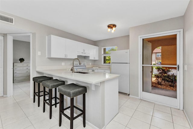 25100 Sandhill Blvd Unit R104, Punta Gorda, FL 33983 - kitchen featuring white appliances, under cabinet range hood, a peninsula, a sink, and light countertops