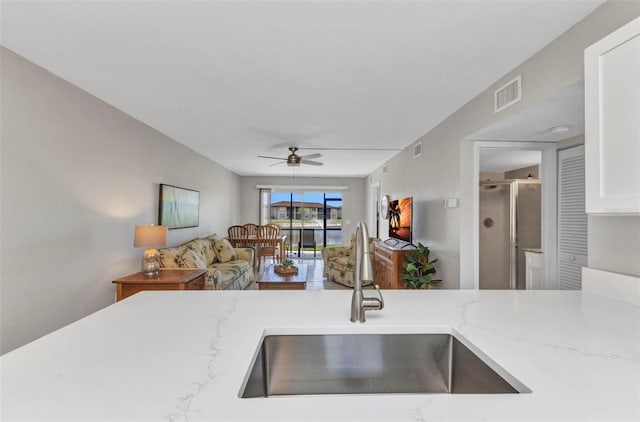 25100 Sandhill Blvd Unit R104, Punta Gorda, FL 33983 - kitchen with a sink, a ceiling fan, open floor plan, light stone countertops, and white cabinets