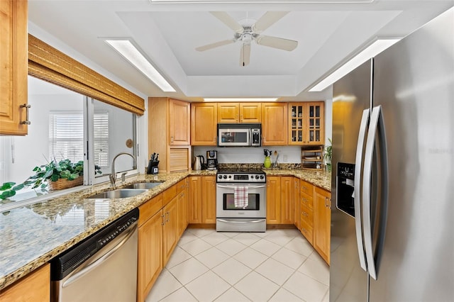 12130 Siesta Dr, Fort Myers Beach, FL 33931 - kitchen featuring glass insert cabinets, appliances with stainless steel finishes, light stone countertops, a sink, and light tile patterned flooring