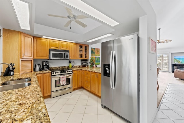 12130 Siesta Dr, Fort Myers Beach, FL 33931 - kitchen featuring glass insert cabinets, light stone countertops, stainless steel appliances, a sink, and light tile patterned flooring