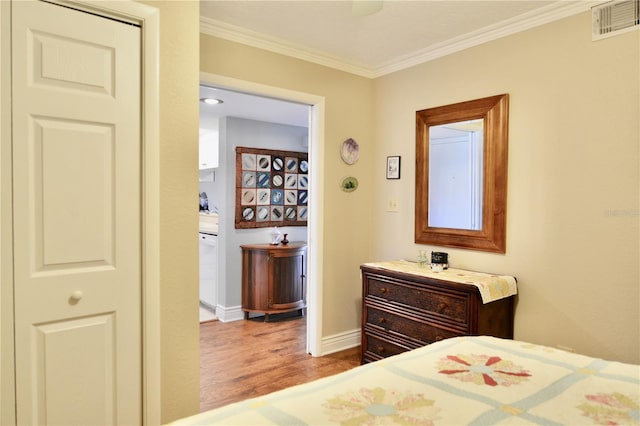 bedroom with ornamental molding, wood finished floors, visible vents, and baseboards