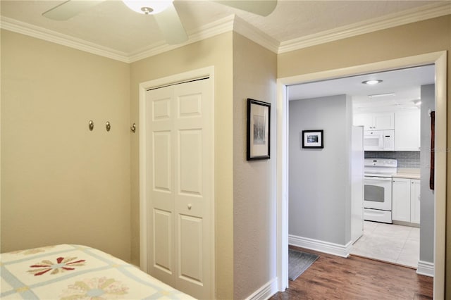 bedroom with ornamental molding, a closet, light wood-type flooring, and baseboards