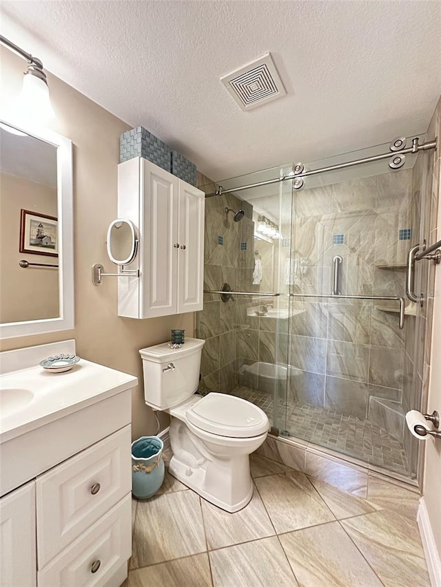 bathroom with visible vents, toilet, a stall shower, vanity, and a textured ceiling