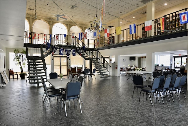 dining space with a paneled ceiling, an inviting chandelier, stairs, and a high ceiling