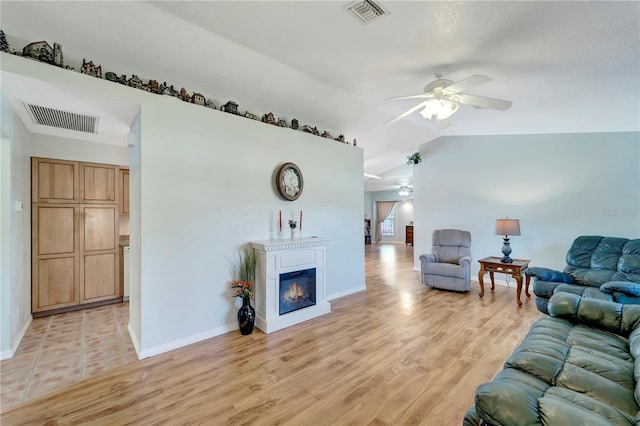 living area with visible vents, light wood-style flooring, a ceiling fan, and vaulted ceiling