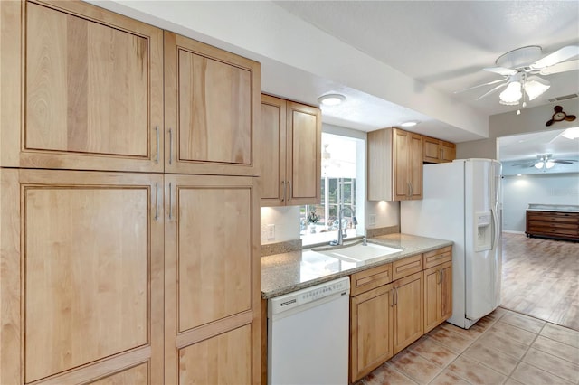 kitchen featuring white appliances, a ceiling fan, light brown cabinetry, and a sink