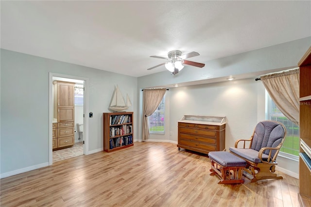 living area with light wood-style flooring, a ceiling fan, and baseboards