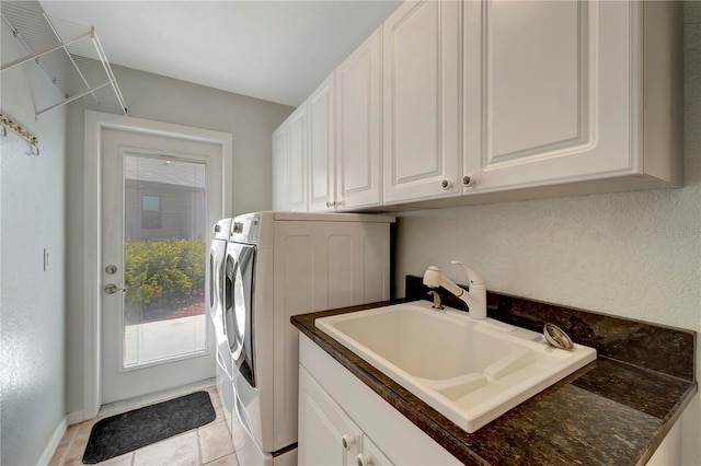 washroom with a sink, light tile patterned floors, cabinet space, and washer and clothes dryer