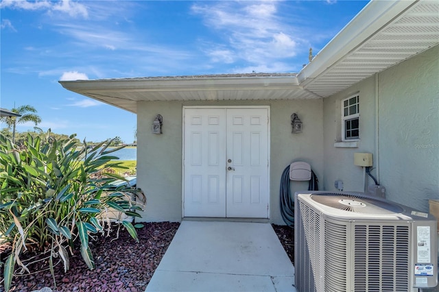 entrance to property featuring central AC unit and stucco siding