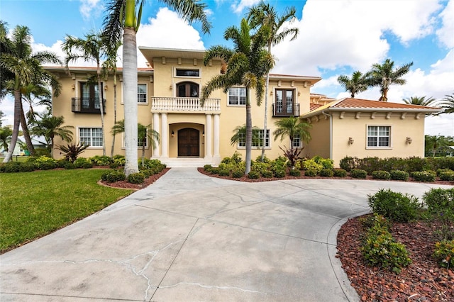 mediterranean / spanish-style house featuring a balcony, stucco siding, and a front yard