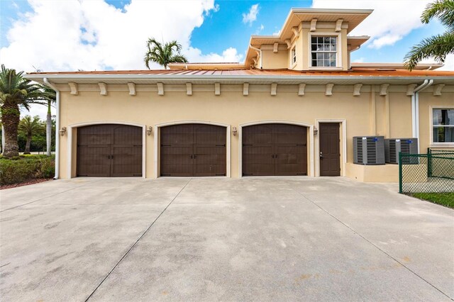 garage with concrete driveway and central air condition unit