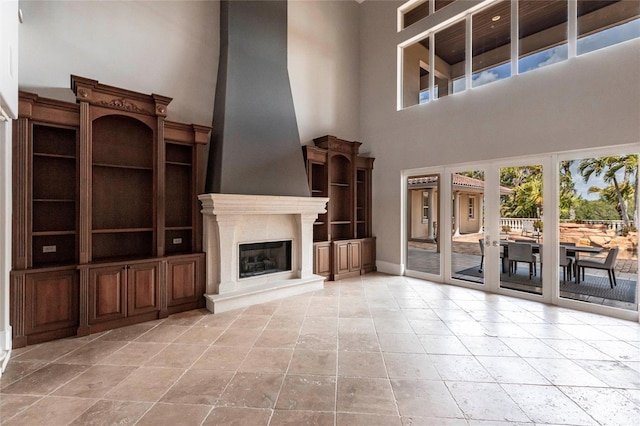 unfurnished living room with a fireplace and a towering ceiling