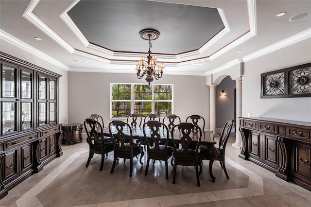 dining space featuring a tray ceiling, recessed lighting, arched walkways, a notable chandelier, and ornate columns