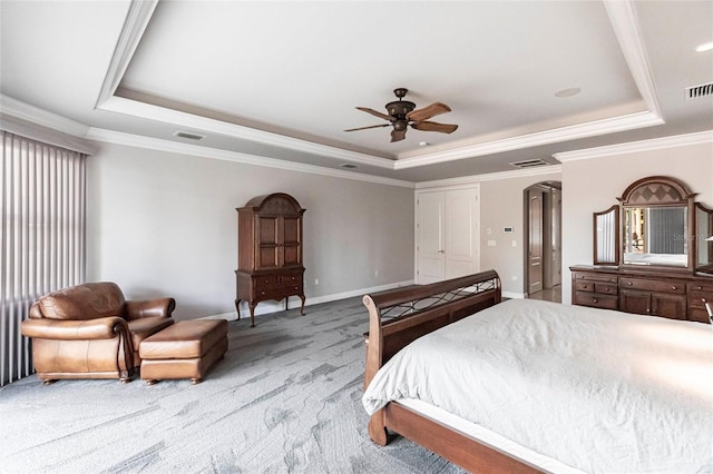 carpeted bedroom with a tray ceiling, arched walkways, baseboards, and crown molding