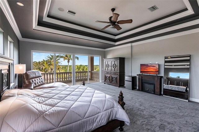 bedroom featuring a glass covered fireplace, a raised ceiling, and visible vents