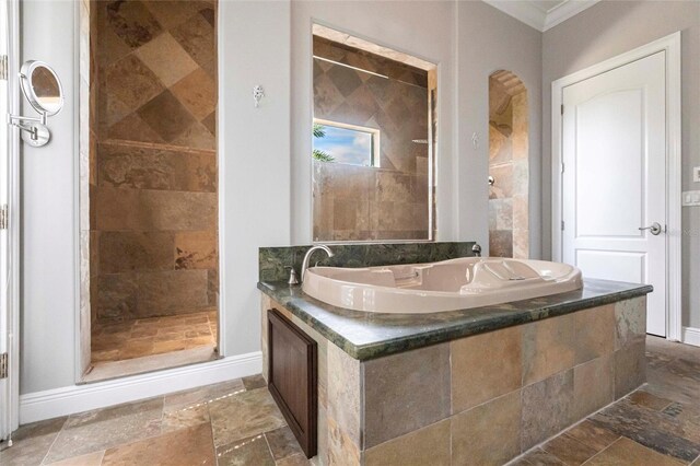 bathroom featuring a stall shower, baseboards, stone tile flooring, and ornamental molding