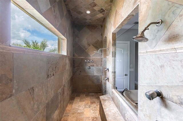 bathroom featuring a walk in shower, a bathtub, and stone finish flooring