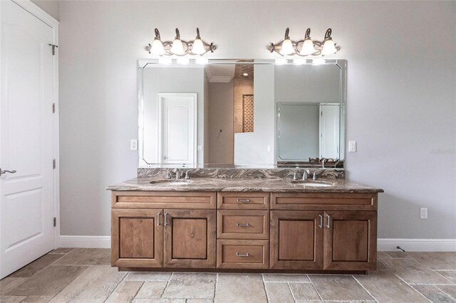 bathroom featuring double vanity, baseboards, and a sink