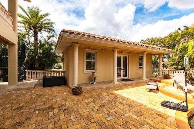 back of property featuring french doors, a patio, a tile roof, and stucco siding