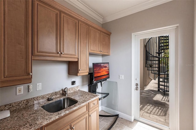 kitchen featuring crown molding, light stone counters, baseboards, and a sink