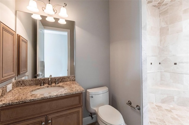 bathroom with toilet, an inviting chandelier, vanity, and a tile shower