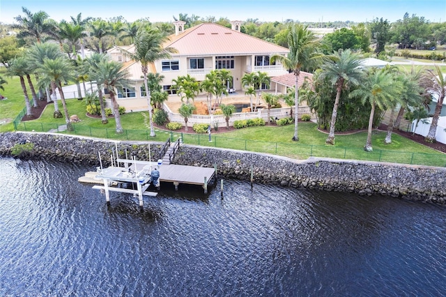 view of dock featuring a lawn, a water view, a fenced backyard, and boat lift