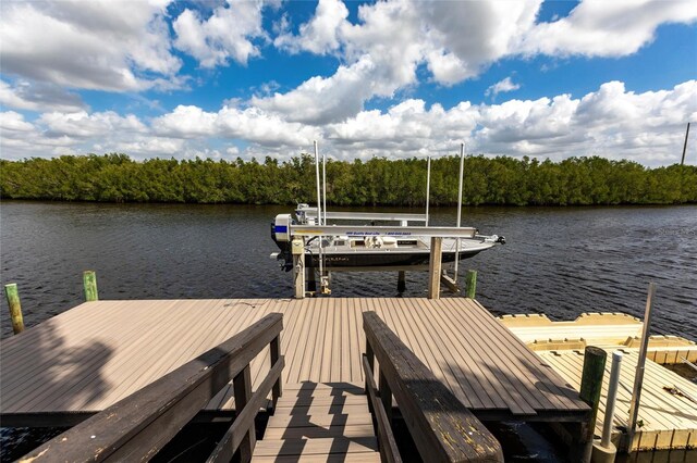 view of dock with a water view, boat lift, and a view of trees