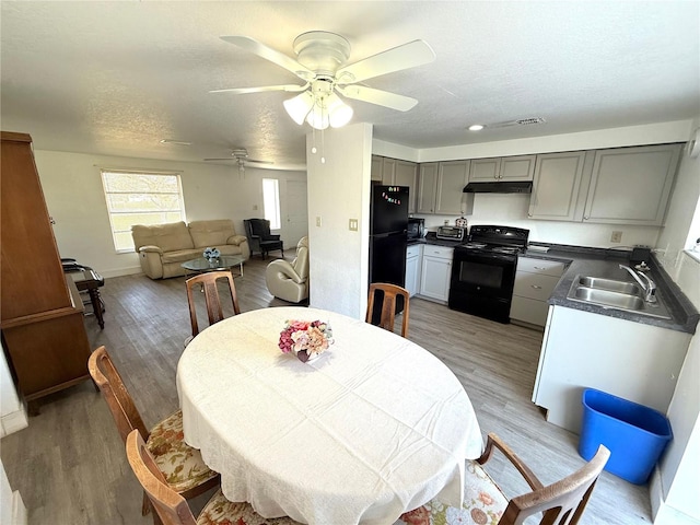 dining space with ceiling fan, a textured ceiling, baseboards, and wood finished floors