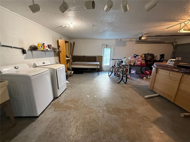 laundry room with concrete block wall, a textured ceiling, and washing machine and clothes dryer