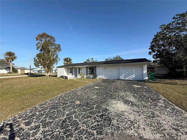 ranch-style house featuring a garage, aphalt driveway, and a front yard