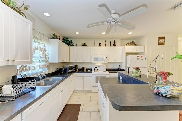 315 Southland Rd, Venice, FL 34293 - kitchen with dark countertops, white appliances, white cabinets, and a sink