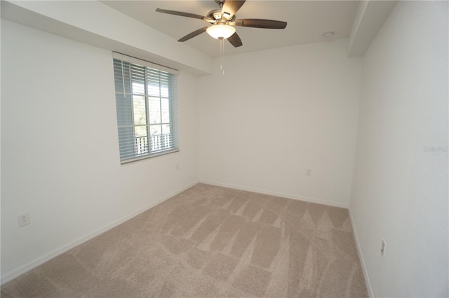 spare room with ceiling fan, baseboards, and light colored carpet